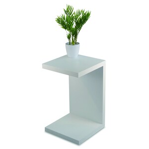 May include: White side table with a single shelf. The table has a modern design and is made of wood. A small potted plant sits on the top shelf.