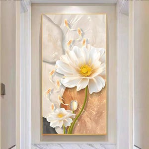 May include: Floral wall art featuring two large white flowers with yellow centers and green stems. The background has a neutral color palette with beige, brown, and gray tones. The artwork is framed in a gold-colored frame.