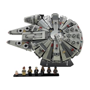 Puede incluir: Un modelo detallado de la nave espacial Millennium Falcon construido con ladrillos de plástico entrelazados. La nave gris y blanca presenta detalles intrincados y está acompañada de varias figuras de personajes en miniatura, todo sobre un fondo blanco.