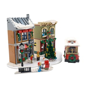 May include: A Christmas-themed Lego set featuring a Main Street scene with buildings, a trolley, and a Christmas tree. The buildings are brick-built with snow-covered roofs and festive decorations. A clock tower and street sign are also included.