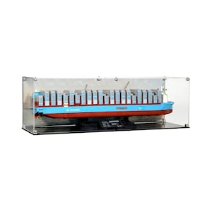 Puede incluir: Maqueta de un gran buque de carga, pintado en azul claro y rojo, con numerosos contenedores apilados. El modelo se exhibe dentro de una vitrina de acrílico transparente, mostrando el diseño y los detalles del barco.