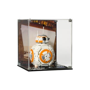 May include: A white and orange BB-8 Lego Star Wars droid figure displayed inside a clear acrylic display case. The droid has a spherical body with orange and grey circular details. The display case has a black base and a printed background.