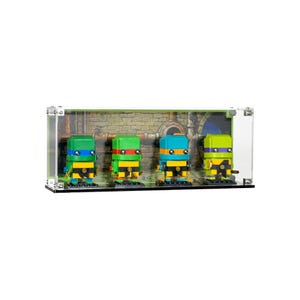 May include: A display case featuring four Teenage Mutant Ninja Turtle figures. Each figure is a different color: green, red, blue, and yellow. The figures are in a clear display case with a sewer backdrop.