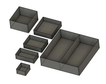 May include: A collection of seven dark gray storage containers of varying sizes. The containers are rectangular and square, with open tops. The largest container is divided into two sections. The containers are arranged on a white background.