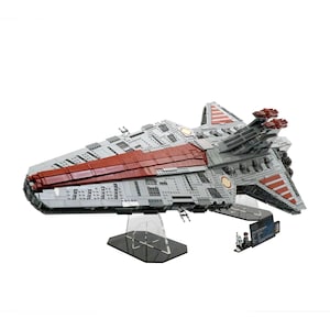 May include: A gray and red LEGO Star Wars Republic Attack Cruiser with a minifigure. The cruiser has a long, narrow design with a pointed nose and a large, flat wingspan. The cruiser is sitting on a black display stand.