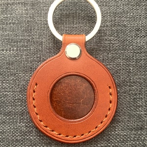 May include: A brown leather keychain with a stitched circle and a metal ring. The circle has a smaller circle cut out of the center.