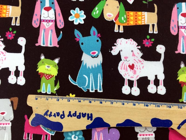 May include: A fabric with a repeating pattern of cartoon dogs in various colors, including pink, blue, green, and tan, on a dark brown background. The dogs have different designs and accessories. A wooden ruler with the text "Happy Party" is at the bottom.