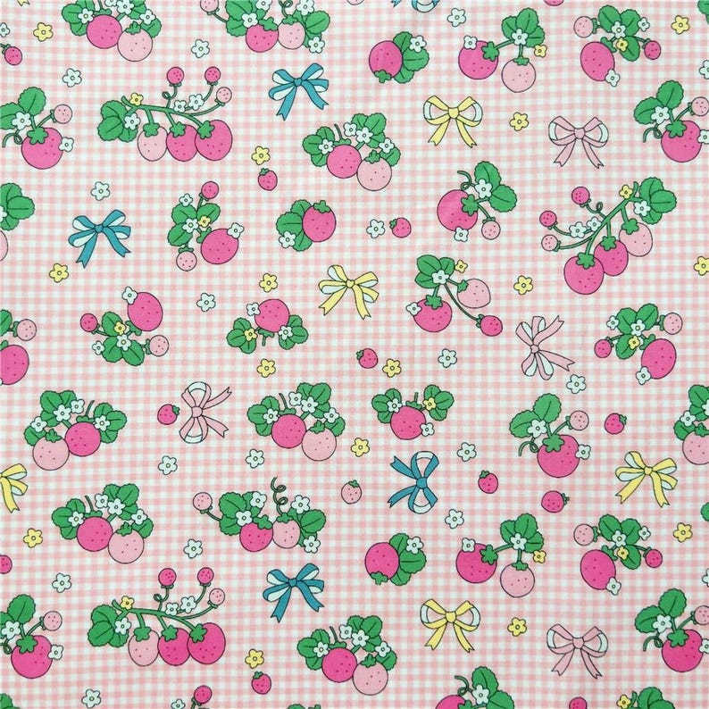 Peut inclure: Motif r&eacute;p&eacute;t&eacute; de fraises roses avec des feuilles vertes et des fleurs blanches sur un fond vichy rose et blanc. Le motif comprend &eacute;galement des n&oelig;uds bleus, jaunes et roses. Ce tissu convient &agrave; divers projets d'artisanat.