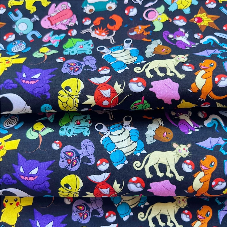 May include: Black fabric with a repeating pattern of colorful cartoon characters. The characters are from the Pokemon franchise and include Pikachu, Charmander, Squirtle, Bulbasaur, and many more.