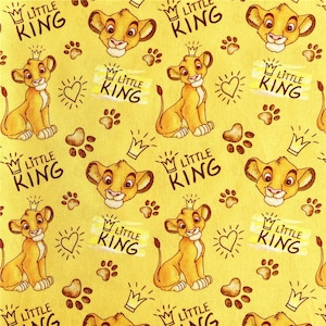 Puede incluir: Una tela amarilla con un patr&oacute;n repetido de un cachorro de le&oacute;n de dibujos animados con una corona y las palabras "Little King".
