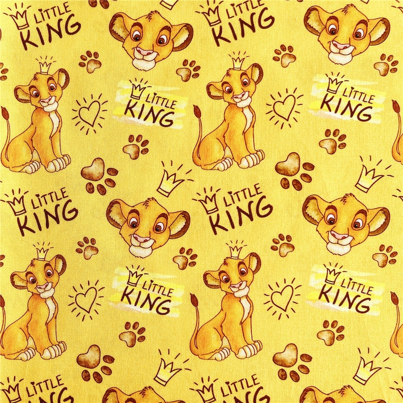 Puede incluir: Una tela amarilla con un patr&oacute;n repetido de un cachorro de le&oacute;n de dibujos animados con una corona y las palabras "Little King".