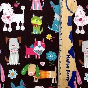 May include: A black fabric featuring a repeating pattern of colorful cartoon dogs, flowers, and hearts. The dogs are in various poses and colors, including pink, blue, green, and gray. A wooden ruler with blue and white accents is in the image.