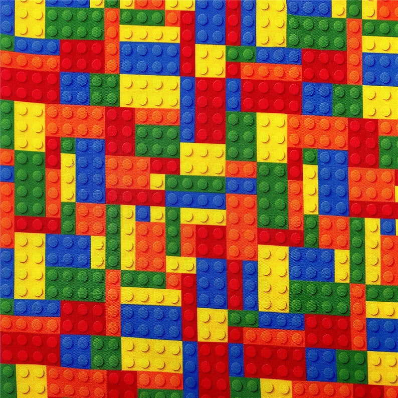 K&ouml;nnte beinhalten: Ein farbenfroher Stoff mit einem sich wiederholenden Muster aus roten, gelben, blauen und gr&uuml;nen Lego-Steinen.