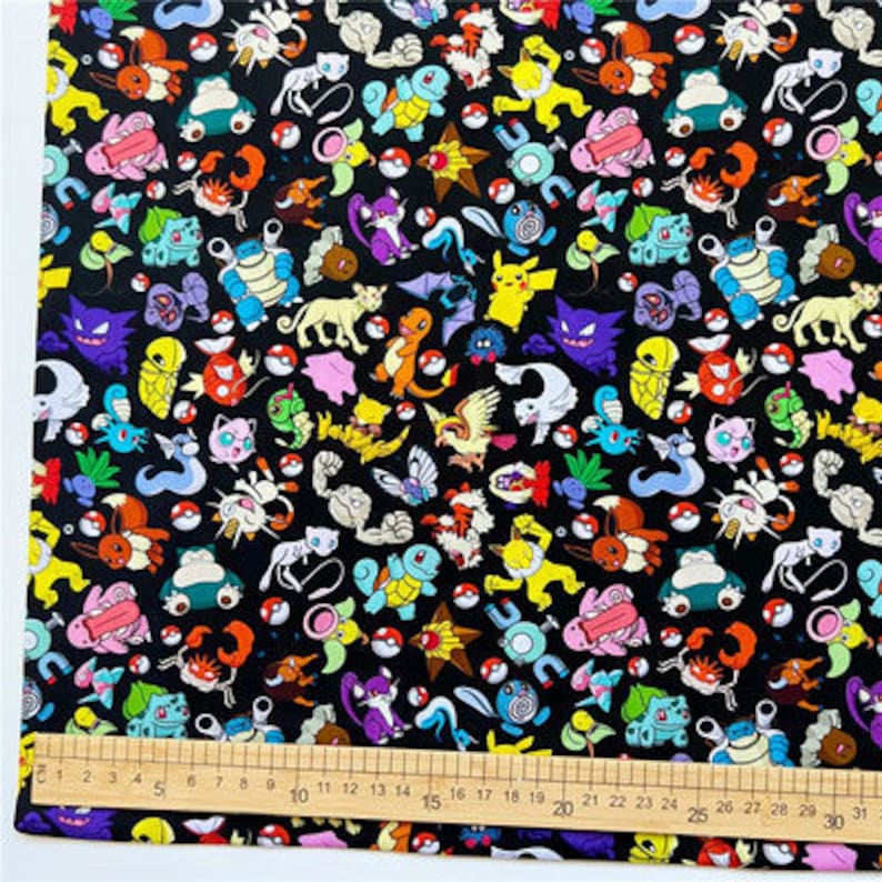 May include: Black fabric with a repeating pattern of colorful cartoon characters. The characters are from the Pokemon franchise and include Pikachu, Bulbasaur, Charmander, Squirtle, and many more.