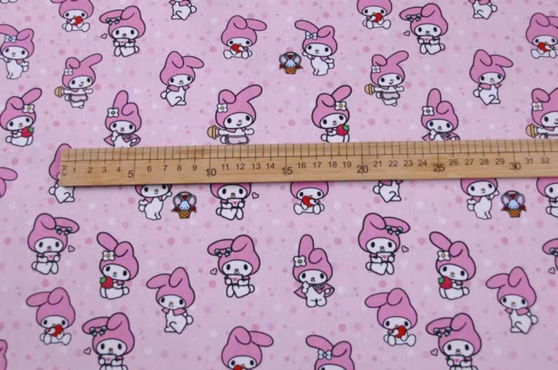 May include: Pink fabric with a repeating pattern of a cartoon bunny holding a strawberry. The bunny is wearing a pink dress and a white bow. The background is a light pink with white polka dots.