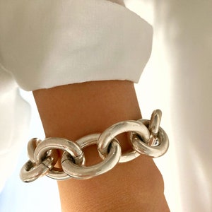 May include: A silver chunky chain bracelet with large, rounded links.
