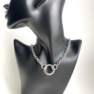 May include: A silver chain necklace with a large, round, silver pendant.