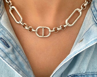 May include: A silver chain necklace with a large oval link design. The necklace is made of metal and has a polished finish.