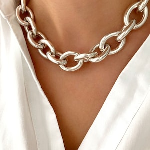 Könnte beinhalten: Eine dicke silberne Kettenkette mit großen, ovalen Gliedern.