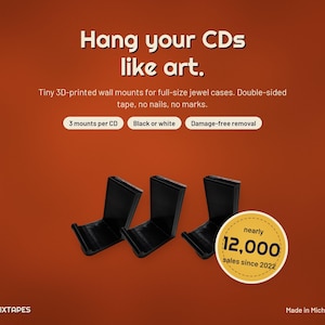 Pode incluir: Três suportes de parede pretos impressos em 3D para caixas de CD. O texto diz: Hang your CDs like art. Tiny 3D-printed wall mounts for full-size jewel cases. Double-sided tape, no nails, no marks. 3 mounts per CD, Black or white, Damage-free removal.