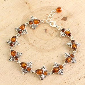 May include: A silver bracelet with amber bee charms. The bracelet has a lobster clasp closure.