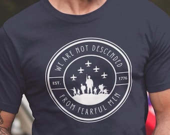 May include: A navy blue t-shirt with a white circle graphic. The graphic features the text "We are not descended from fearful men" with the year "1776" and the words "Est. 1776" inside the circle. The graphic also includes a silhouette of soldiers and airplanes.