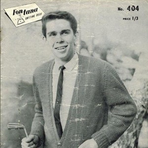 May include: A black and white photo of a man wearing a knitted cardigan with a button-up shirt and tie. The cardigan is a textured knit with a v-neck. The man is holding a golf club in his left hand. The photo is from a vintage knitting book.