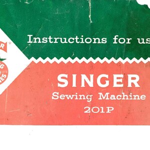 以下が含まれることがあります： 緑と赤のヴィンテージのシンガーミシン取扱説明書で、"Instructions for using Singer Sewing Machine 201P"というテキストが書かれています。