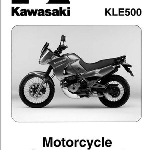 Op de afbeelding: Zwart-wit afbeelding van een Kawasaki KLE500 motorfiets. De motorfiets is zilverkleurig met zwarte banden en een zwart zadel. Het Kawasaki-logo en de woorden "Motorcycle Service Manual" zijn ook zichtbaar.