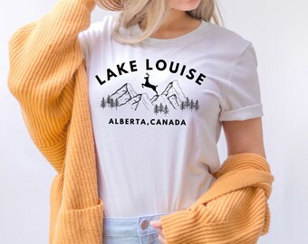 May include: White t-shirt with a black graphic design of mountains, a deer, and the text "LAKE LOUISE ALBERTA, CANADA".