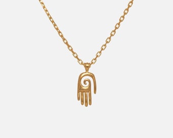 Pode incluir: Um colar de tom dourado com um pingente em forma de mão estilizada que apresenta um design em espiral no centro. O pingente está suspenso por uma delicada corrente de tom dourado com elos ovais, criando uma peça de joalharia simples e coesa.