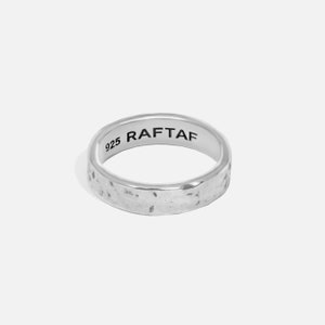 Könnte beinhalten: Ein silberner Ring mit gehammerter Textur. Der Ring trägt den Text "925 RAFTAF" auf der Innenseite. Der Ring ist ein einfacher Bandstil, geeignet für den täglichen Gebrauch.