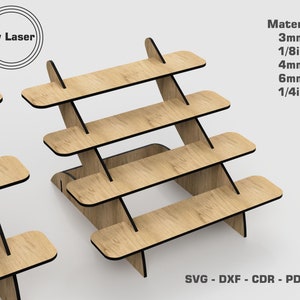May include: A four-tier wooden display stand with black edges. The stand is made of 3mm, 4mm, and 6mm thick wood. The stand is angled and has a modern design. The text "By Laser" is visible in the image. The text "Material 3mm 1/8in 4mm 6mm 1/4in SVG - DXF - CDR - PDF - AI" is also visible in the image.
