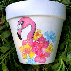 Peut inclure: Pot en céramique blanche avec un flamant rose peint à la main et des fleurs jaunes, roses et bleues.