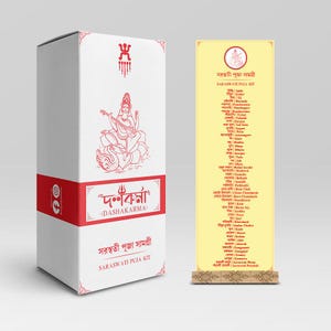 May include: A white box with red accents and the text "Dashkarma" in red. The box features a depiction of a Hindu goddess playing a musical instrument. The text "Saraswati Puja Kit" is printed on the box. A yellow banner with the text "Saraswati Puja Kit" in Bengali is displayed next to the box.