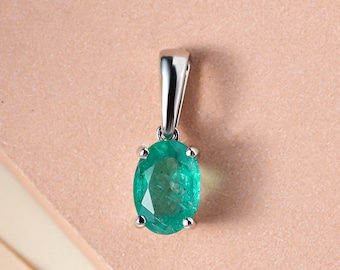May include: A silver pendant with a green oval emerald gemstone.