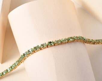 Puede incluir: Un brazalete de cadena dorada con piedras ovaladas de color verde claro.