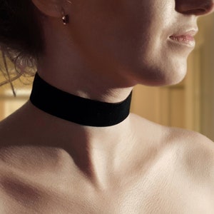 May include: A woman wearing a black strapless dress with a black choker necklace.