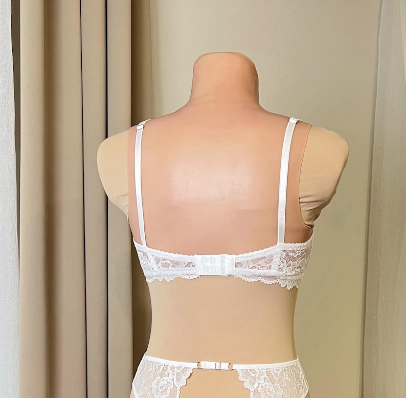 May include: White lace lingerie set with adjustable straps and a delicate floral pattern. The bra has a hook and eye closure in the back. The set is made of soft, stretchy lace.