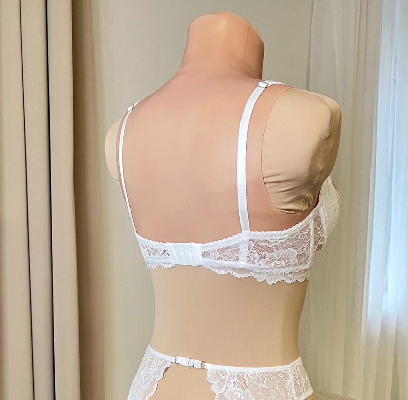 May include: White lace lingerie set with adjustable straps and a hook and eye closure in the back. The set includes a bra and a garter belt.