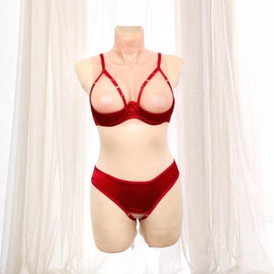 K&ouml;nnte beinhalten: Ein rotes Dessous-Set auf einer Schaufensterpuppe. Das Set besteht aus einem BH mit offenen Cups und einem passenden tief sitzenden Slip. Der BH hat d&uuml;nne Tr&auml;ger und eine samtartige Textur. Der Slip hat ein Schl&uuml;sselloch-Design.