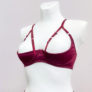 May include: A burgundy satin bra with adjustable straps and a plunging neckline.