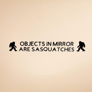 May include: A beige background with black text and silhouettes. The text reads "OBJECTS IN MIRROR ARE SASQUATCHES" with a Sasquatch silhouette on each side of the text. The image is a humorous take on a warning label.