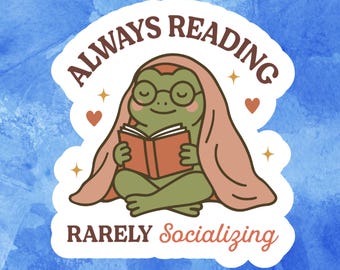 Op de afbeelding: Een sticker met een cartoon kikker met een bril en een deken, die een boek leest. De tekst "ALWAYS READING" staat boven de kikker, met "RARELY Socializing" eronder. De achtergrond is een blauwe aquarel wassing.