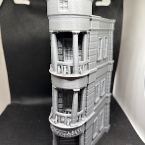 May include: A gray 3D printed model of a building with a domed roof and a sign that reads "Gringotts Bank".