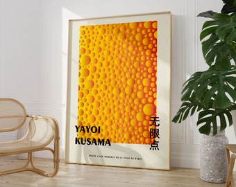 May include: A poster featuring a yellow and orange abstract pattern of overlapping circles. The text "YAYOI KUSAMA" and "無限点" is printed in black at the bottom of the poster. The poster is framed in a light wood frame.