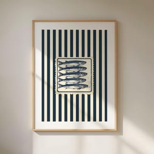 May include: Framed art print featuring a vintage-style illustration of five fish. The fish are in a rectangular stamp design, set against a background of navy blue and cream vertical stripes. The frame is a light wood color.