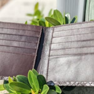 May include: Brown leather wallet with multiple card slots and a small pocket for cash. The wallet is open and the inside is visible.