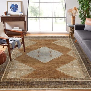 May include: A large, rectangular rug with a geometric design. The rug features a central diamond pattern in light beige and a border in dark brown. The rug's colour palette includes shades of brown, beige, and cream.