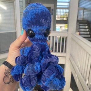 May include: A blue and gray crocheted octopus plush toy with large black eyes.